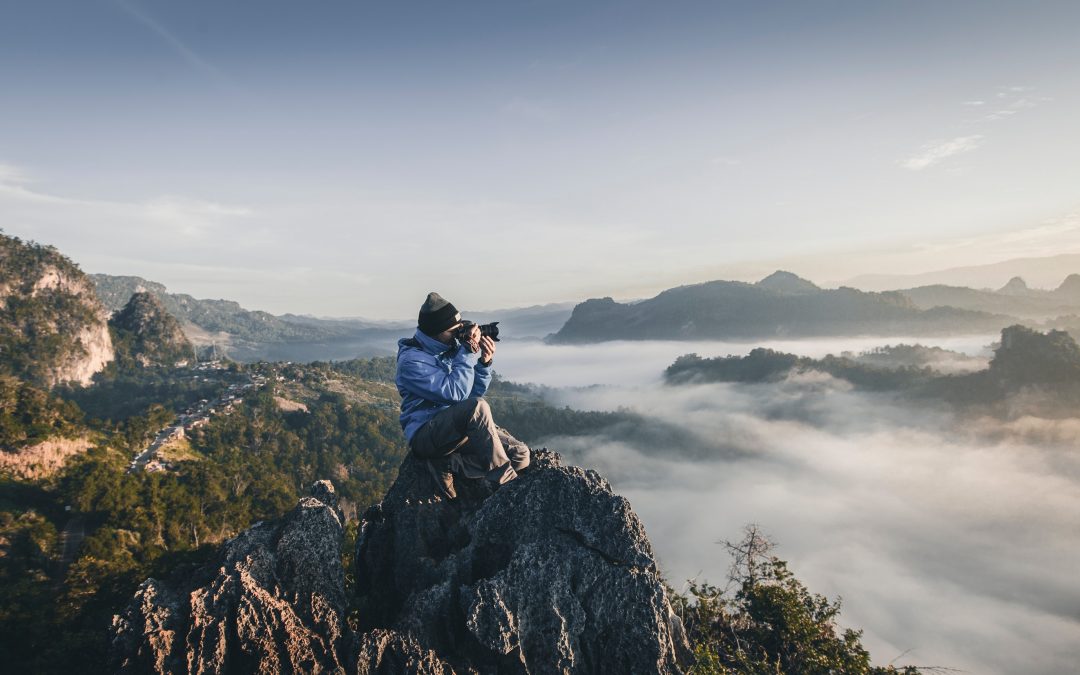 Man on a mountain taking a photo: Creative Ways to Engage Alumni